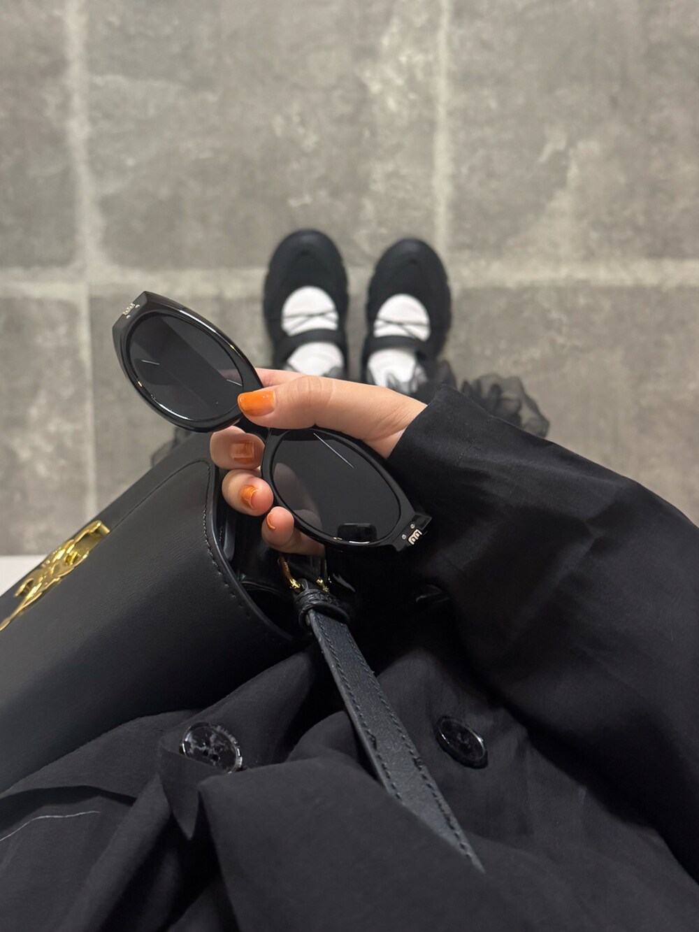 ブラック系のテーラードジャケット、ブラック系のショルダーバッグ、ブラック系のサングラスを着用したレディースの春コーディネートの3枚目の写真