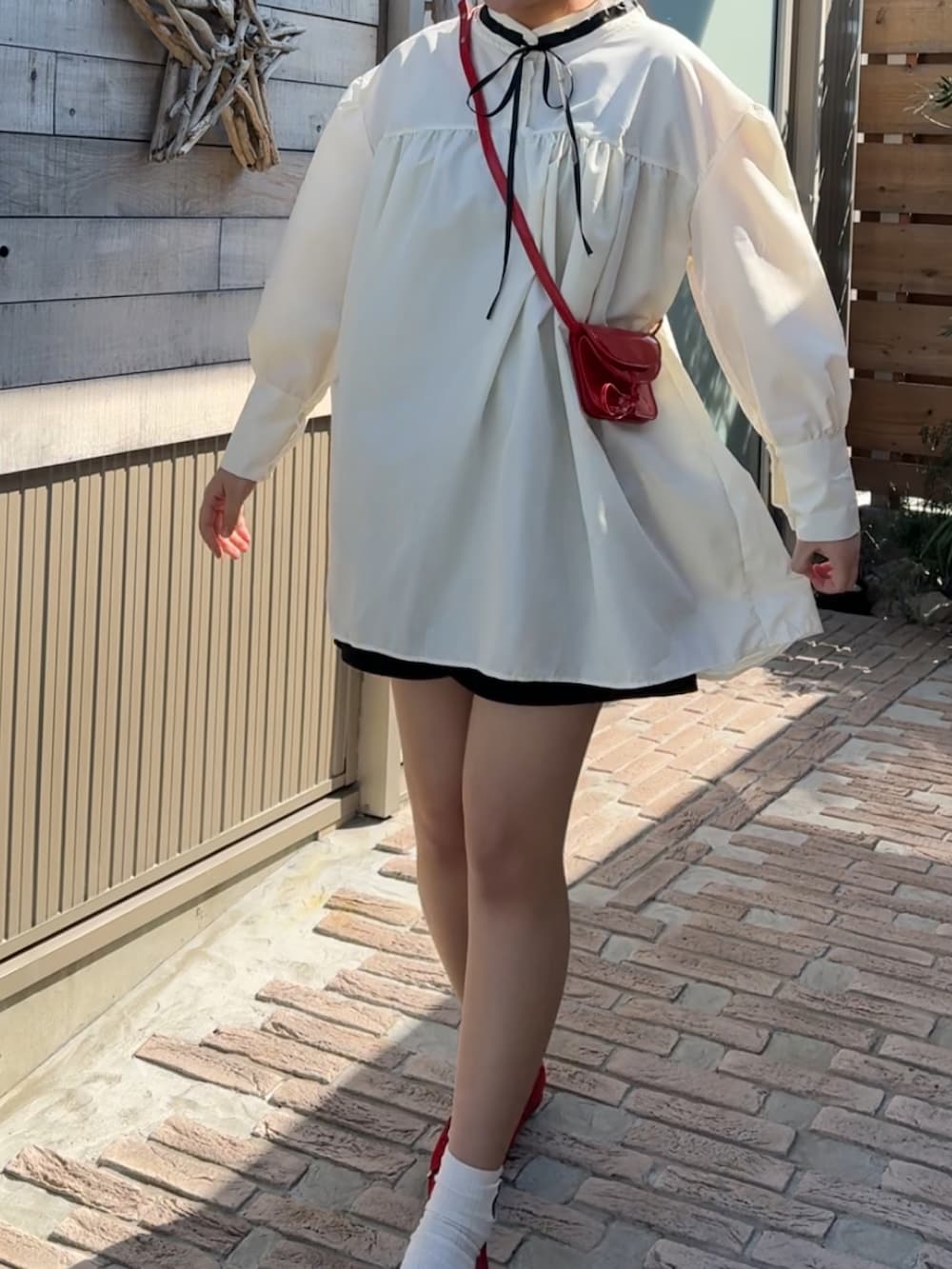 ホワイト系のシャツワンピース、ブルー系のパンプス、レッド系のショルダーバッグを着用したレディースの春コーディネートの2枚目の写真