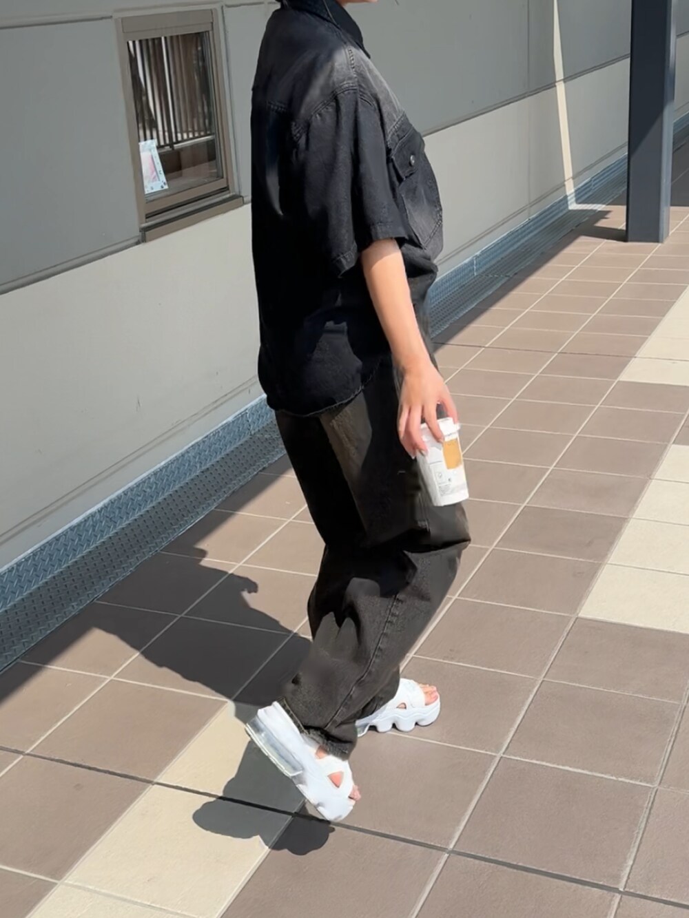 ブラック系のデニムパンツ、ブラック系のシャツ/ブラウス、ホワイト系のサンダルを着用したレディースの春コーディネートの3枚目の写真