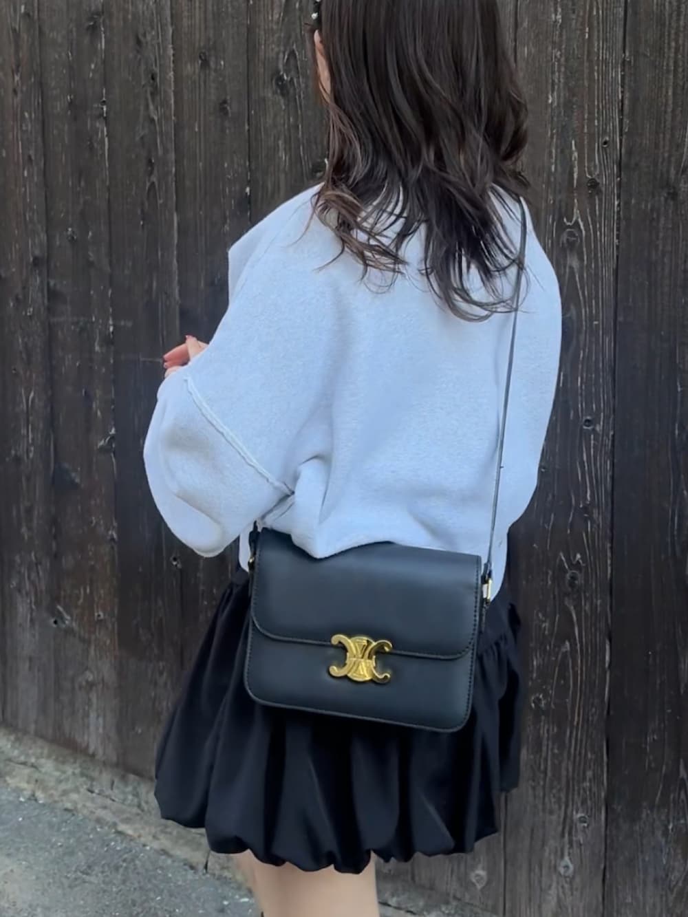 ホワイト系のスウェット、ブラック系のブーツ、ブラック系のショルダーバッグを着用したレディースの冬コーディネートの2枚目の写真