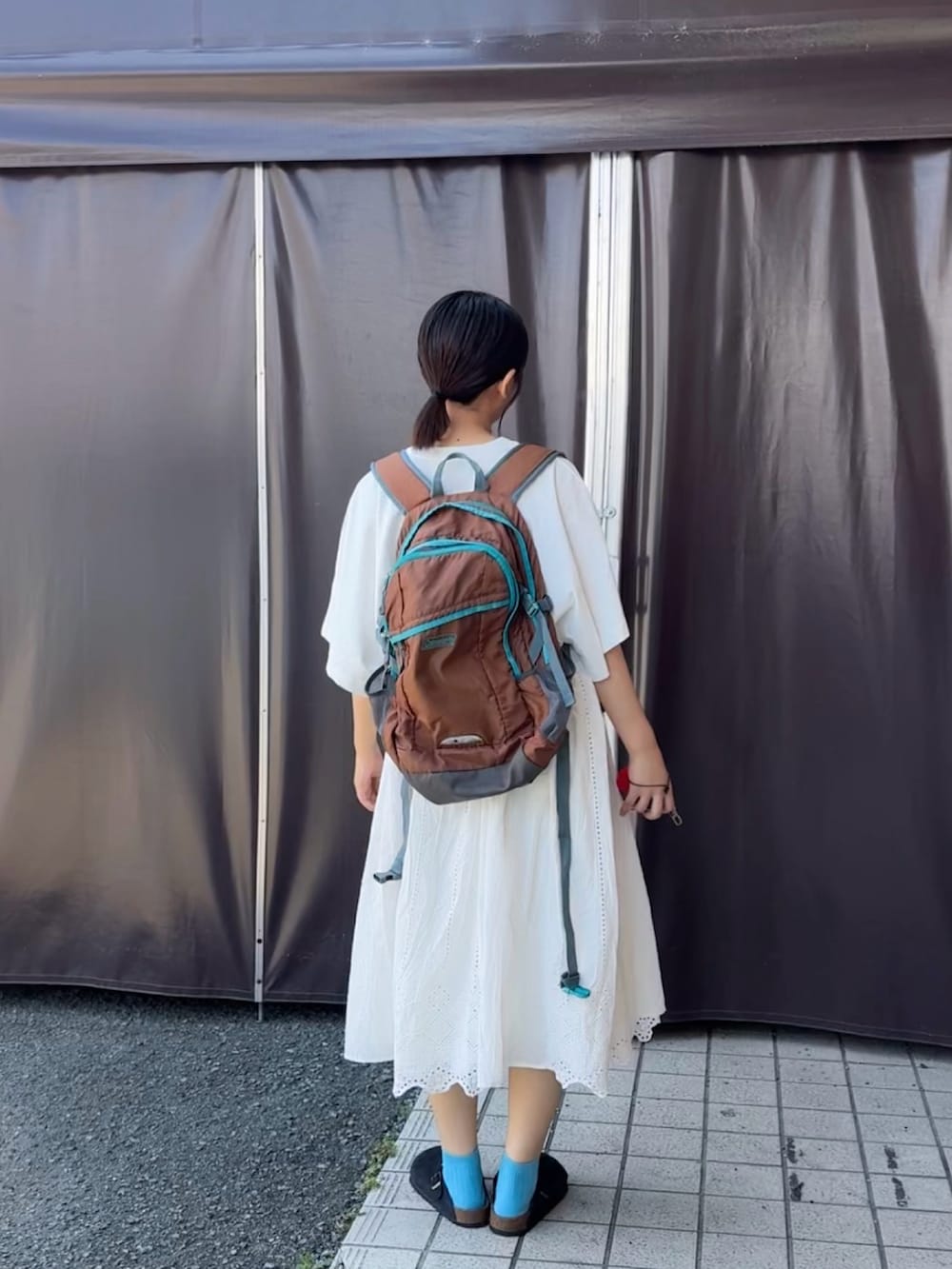 ブラック系のサンダル、ホワイト系のTシャツ/カットソー、ブラウン系のバックパック/リュックを着用したレディースの夏コーディネートの3枚目の写真