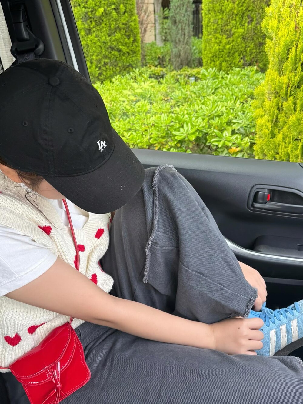 ホワイト系のニット/セーター、グレー系のデニムパンツ、レッド系のショルダーバッグを着用したレディースの春コーディネートの2枚目の写真