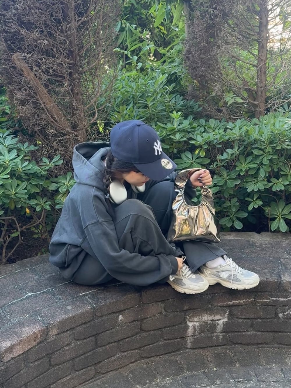 ブラウン系のハンドバッグ、シルバー系のスニーカー、グレー系のパーカーを着用したレディースの秋コーディネートの2枚目の写真