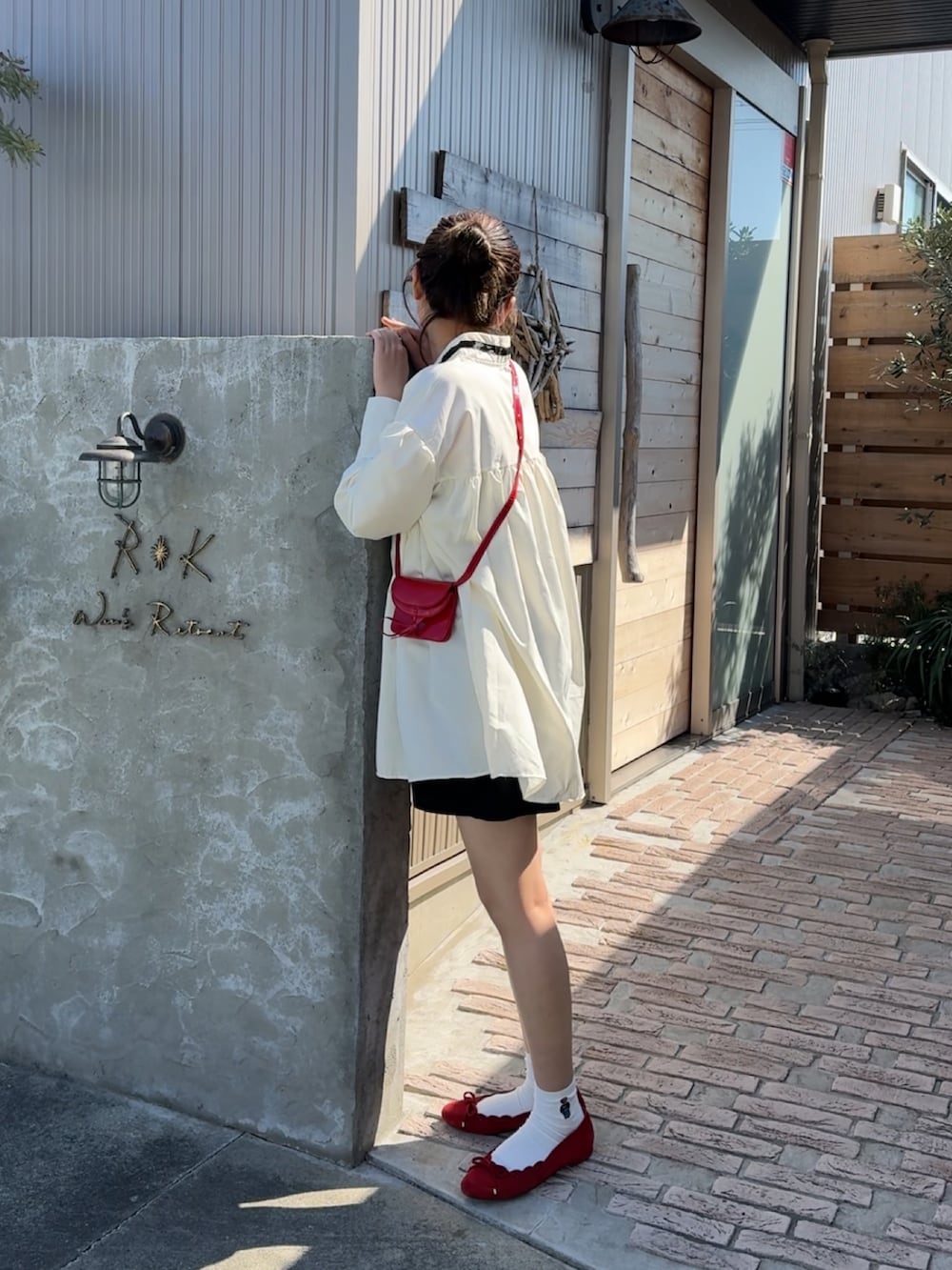 ホワイト系のシャツワンピース、ブルー系のパンプス、レッド系のショルダーバッグを着用したレディースの春コーディネートの3枚目の写真