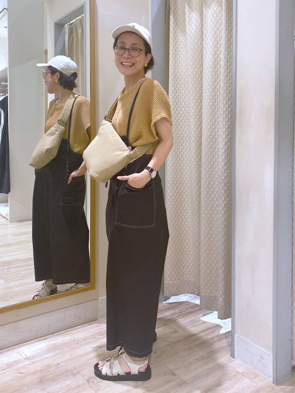 ブラック系のサロペット/オーバーオール、ホワイト系のタンクトップ、ホワイト系のサンダルを着用したレディースの夏コーディネートの3枚目の写真