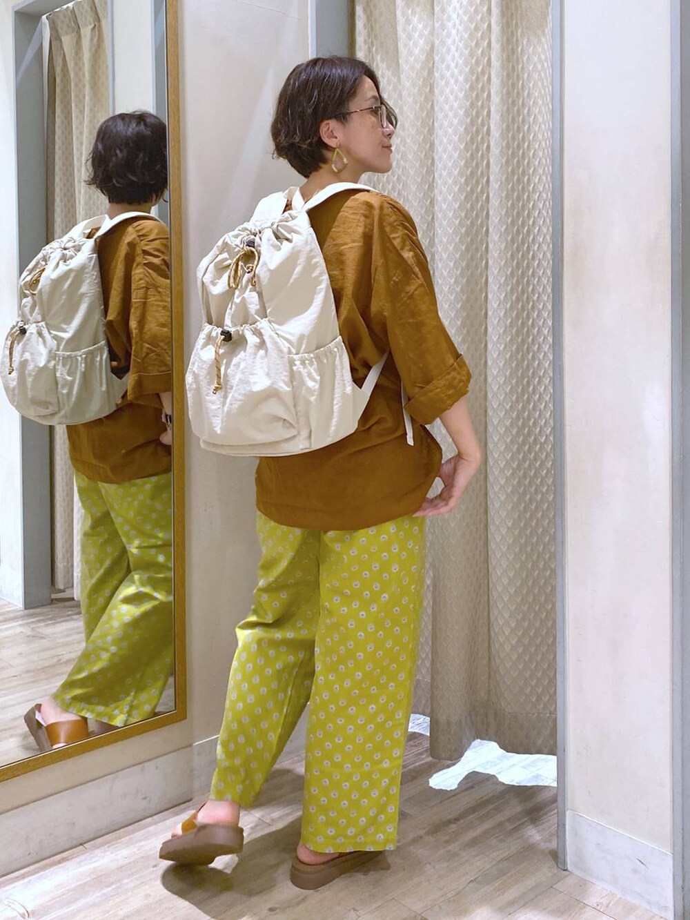 ブラウン系のサンダル、ホワイト系のバックパック/リュック、ホワイト系のタンクトップを着用したレディースの夏コーディネートの5枚目の写真