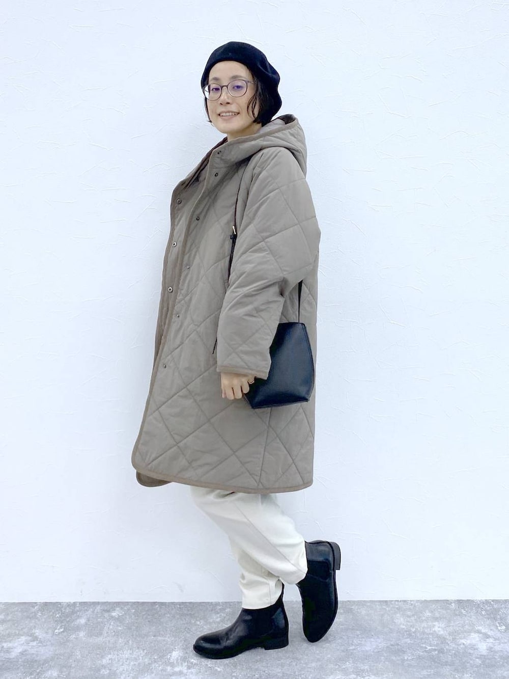 ブラック系のブーツ、ブラウン系のダウンジャケット/コート、ブラック系のショルダーバッグを着用したレディースの冬コーディネートの2枚目の写真