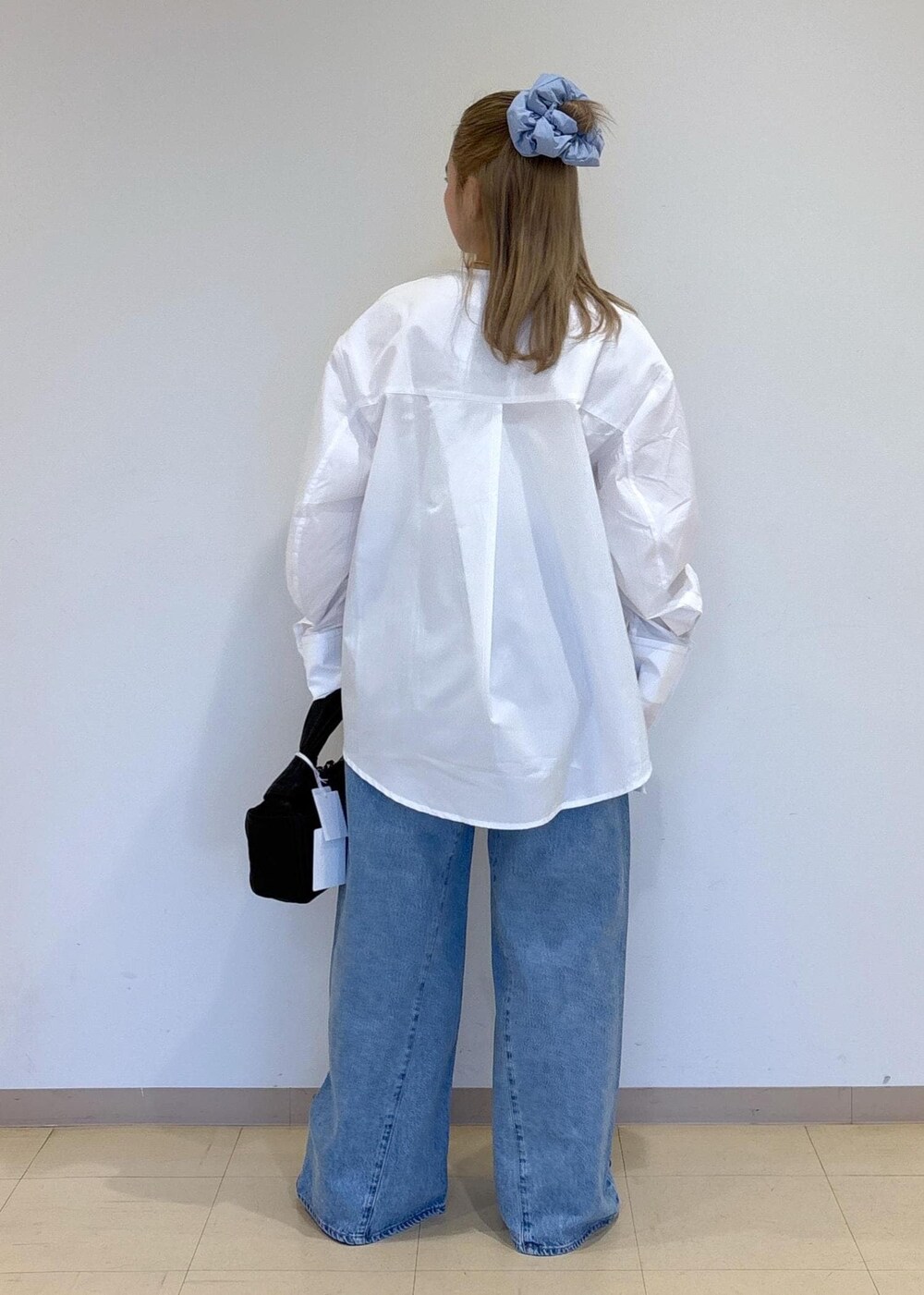 ブルー系のデニムパンツ、ブラック系のサンダル、ブラック系のハンドバッグを着用したレディースの春コーディネートの3枚目の写真