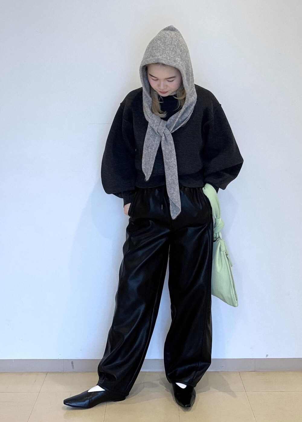 グリーン系のハンドバッグ、ブラック系のパンプス、グレー系のニット/セーターを着用したレディースの秋コーディネートの2枚目の写真