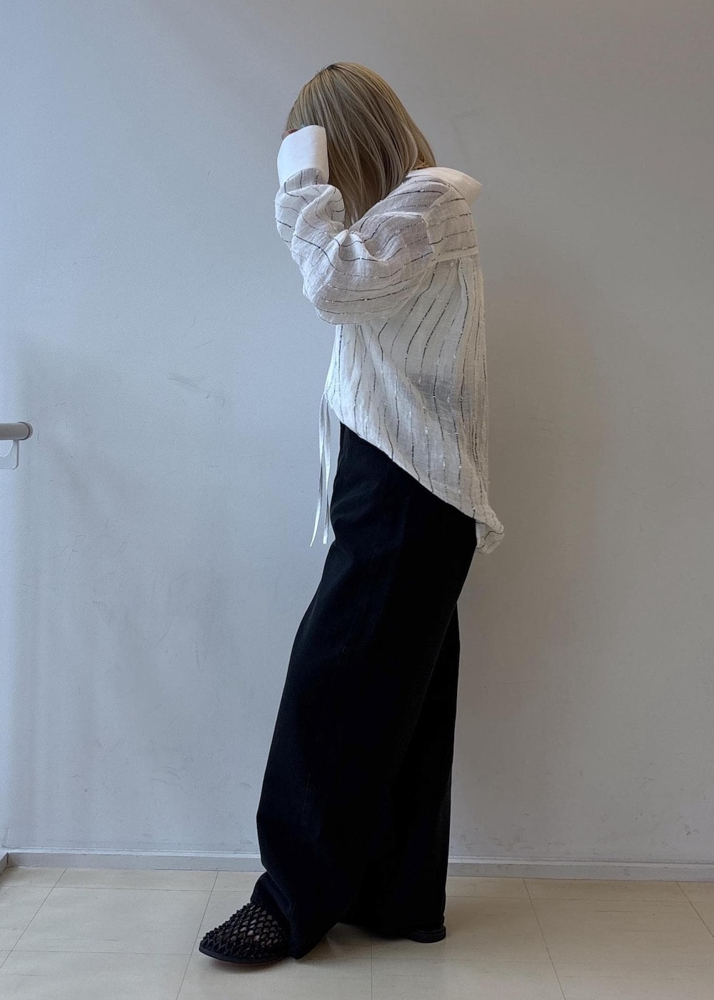 ブラック系のデニムパンツ、ブラック系のサンダル、ホワイト系のシャツ/ブラウスを着用したレディースの夏コーディネートの2枚目の写真