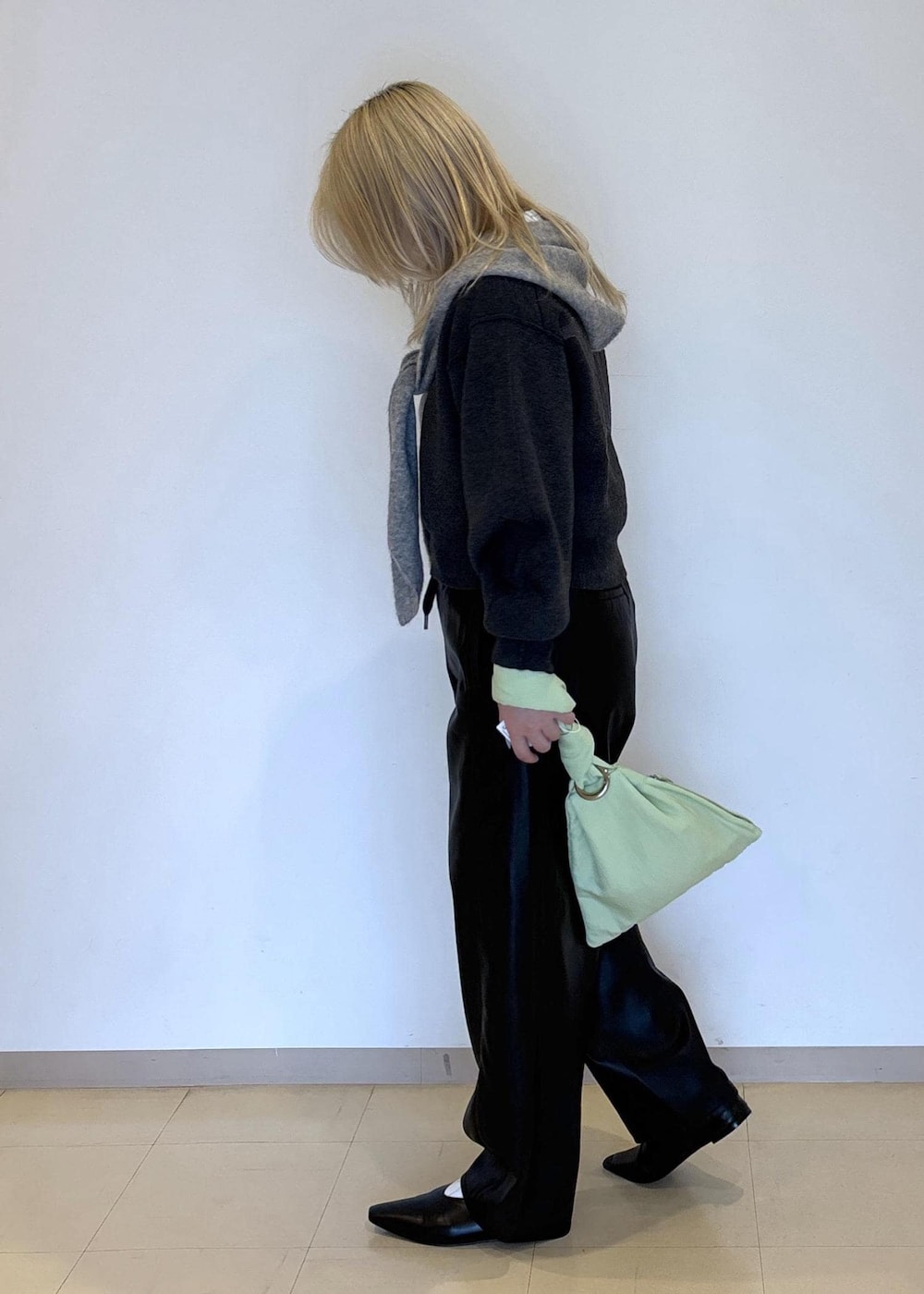 グリーン系のハンドバッグ、ブラック系のパンプス、グレー系のニット/セーターを着用したレディースの秋コーディネートの3枚目の写真