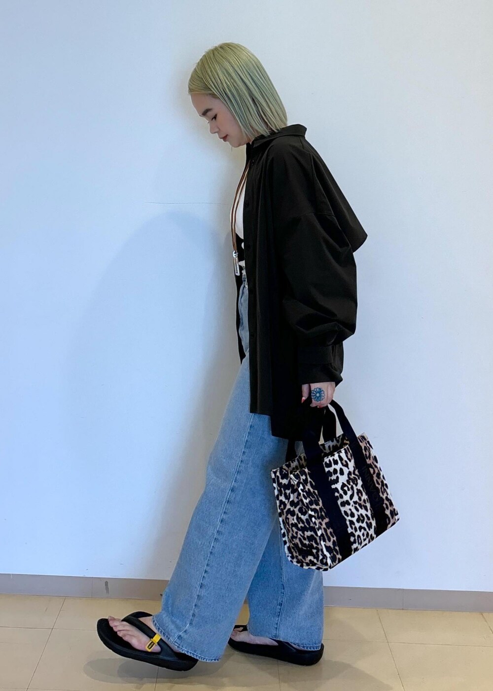 ホワイト系のタンクトップ、ブラウン系のショルダーバッグ、ブルー系のデニムパンツを着用したレディースの春コーディネートの2枚目の写真