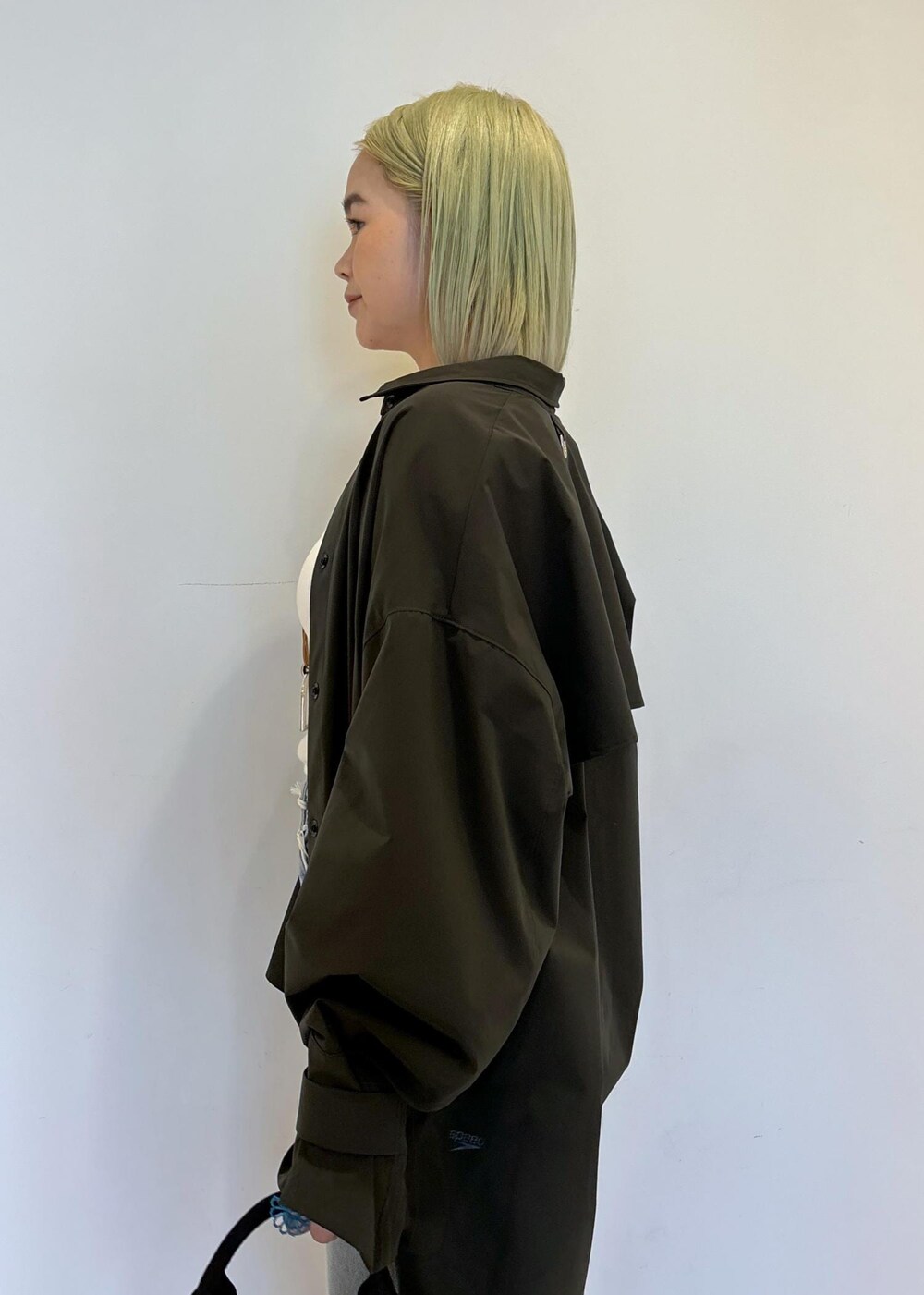 ホワイト系のタンクトップ、ブラウン系のショルダーバッグ、ブルー系のデニムパンツを着用したレディースの春コーディネートの6枚目の写真