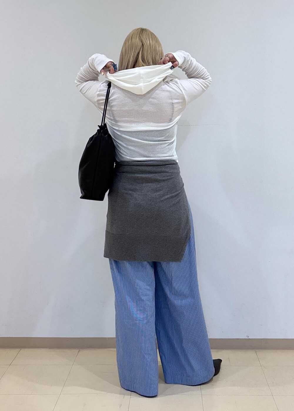 グレー系のニット/セーター、ブラック系のサンダル、ブラック系のショルダーバッグを着用したレディースの秋コーディネートの3枚目の写真