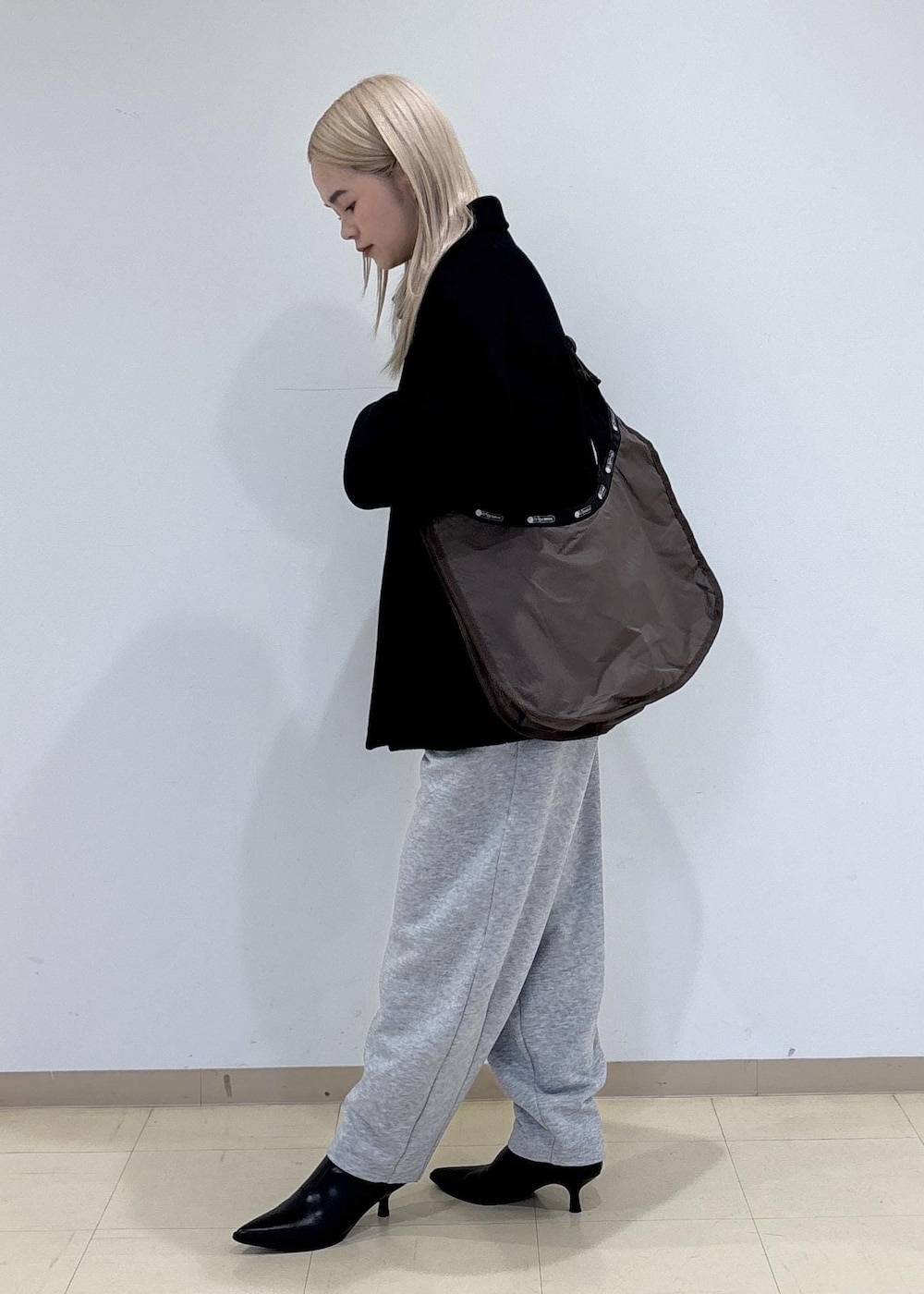 ブラック系のブーツ、グレー系のその他パンツ、ブラウン系のショルダーバッグを着用したレディースの冬コーディネートの2枚目の写真