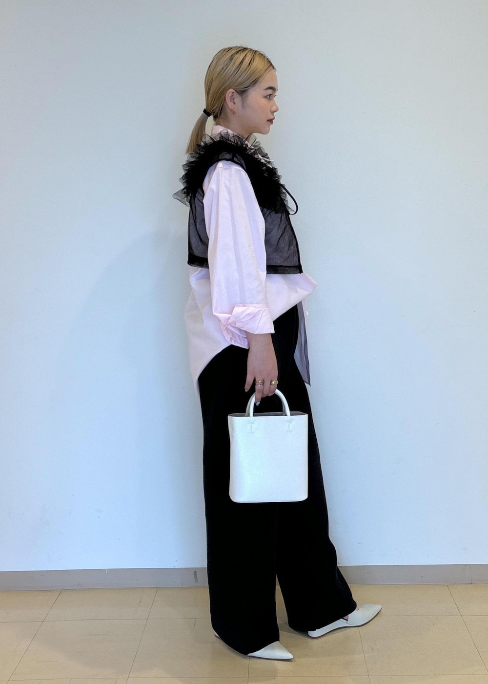 ホワイト系のハンドバッグ、ホワイト系のパンプス、ブラック系のTシャツ/カットソーを着用したレディースの夏コーディネートの3枚目の写真