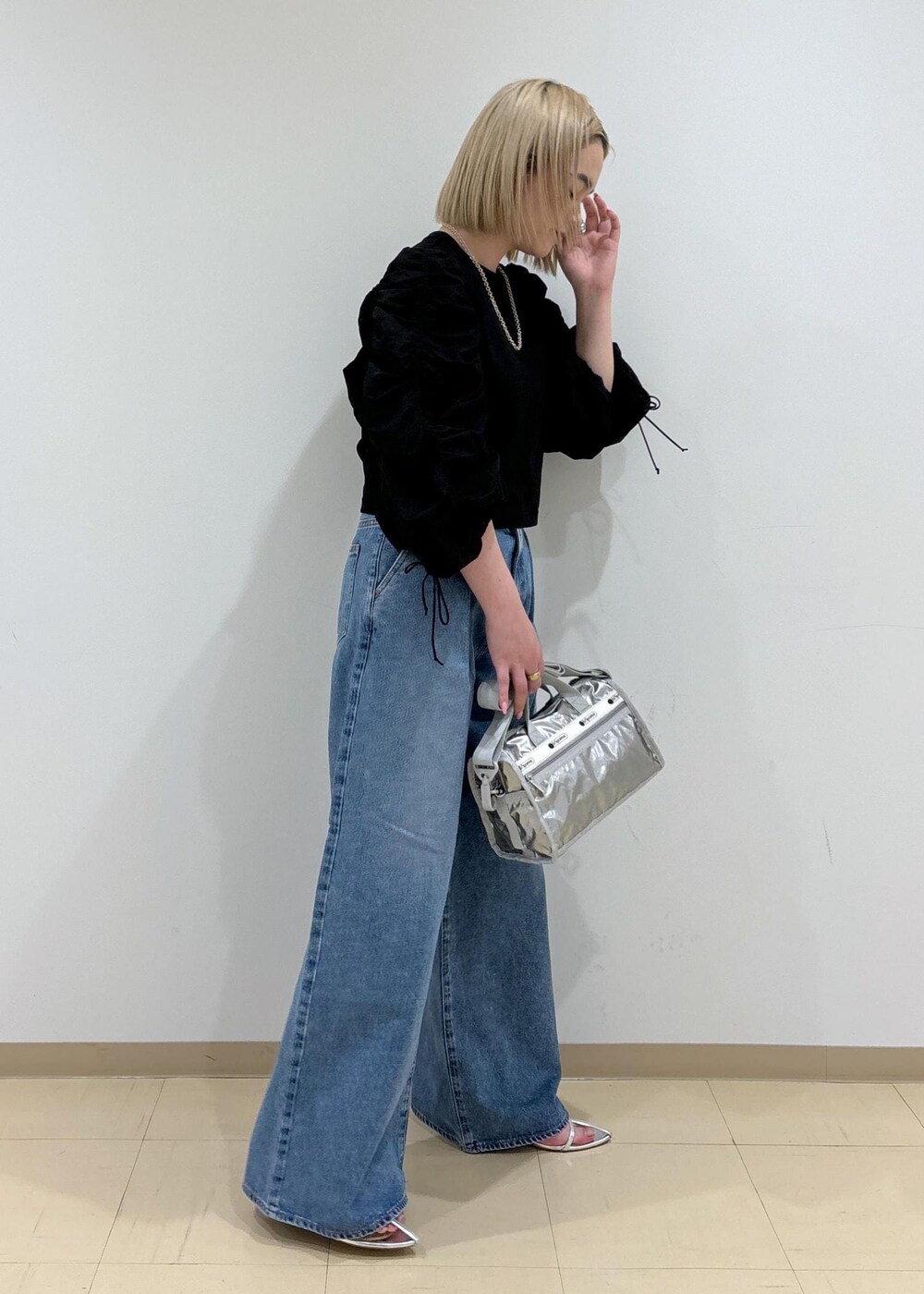 ブルー系のデニムパンツ、シルバー系のショルダーバッグ、シルバー系のサンダルを着用したレディースの春コーディネートの4枚目の写真
