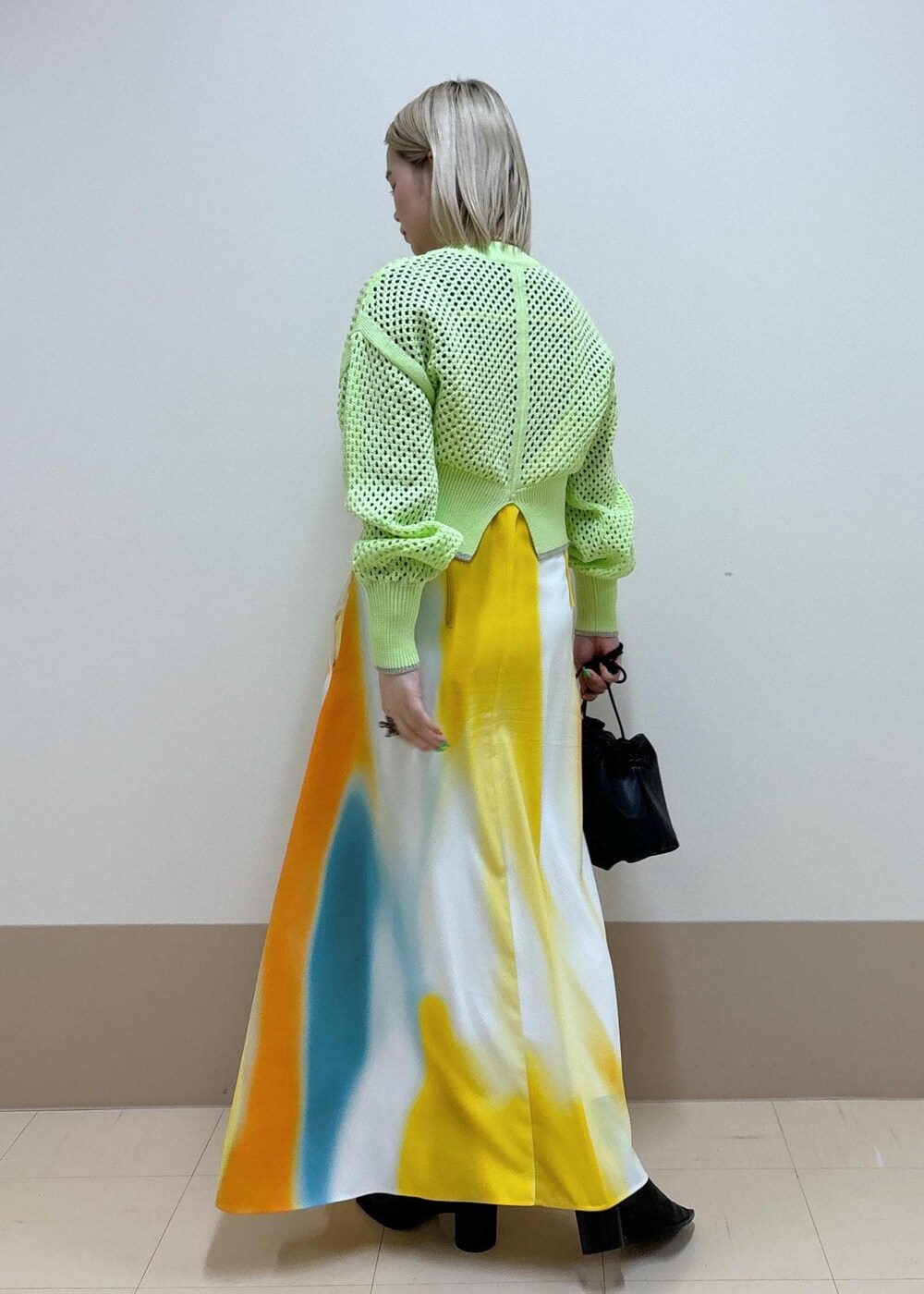 イエロー系のワンピース、ブラック系のショルダーバッグ、ブラック系のブーツを着用したレディースの春コーディネートの3枚目の写真