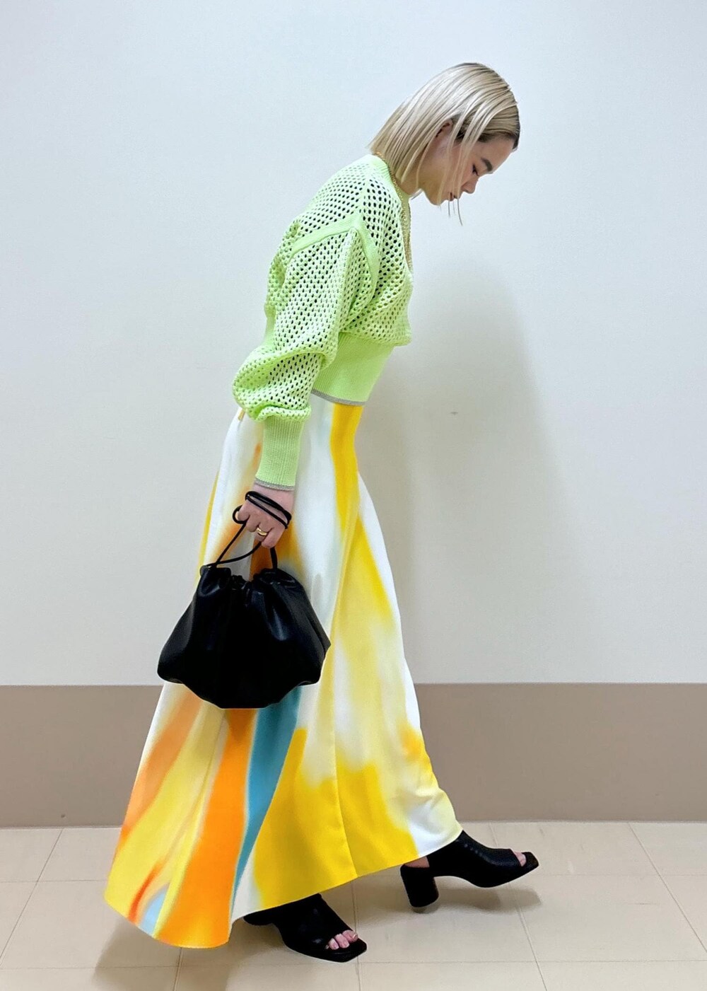 イエロー系のワンピース、ブラック系のショルダーバッグ、ブラック系のブーツを着用したレディースの春コーディネートの5枚目の写真