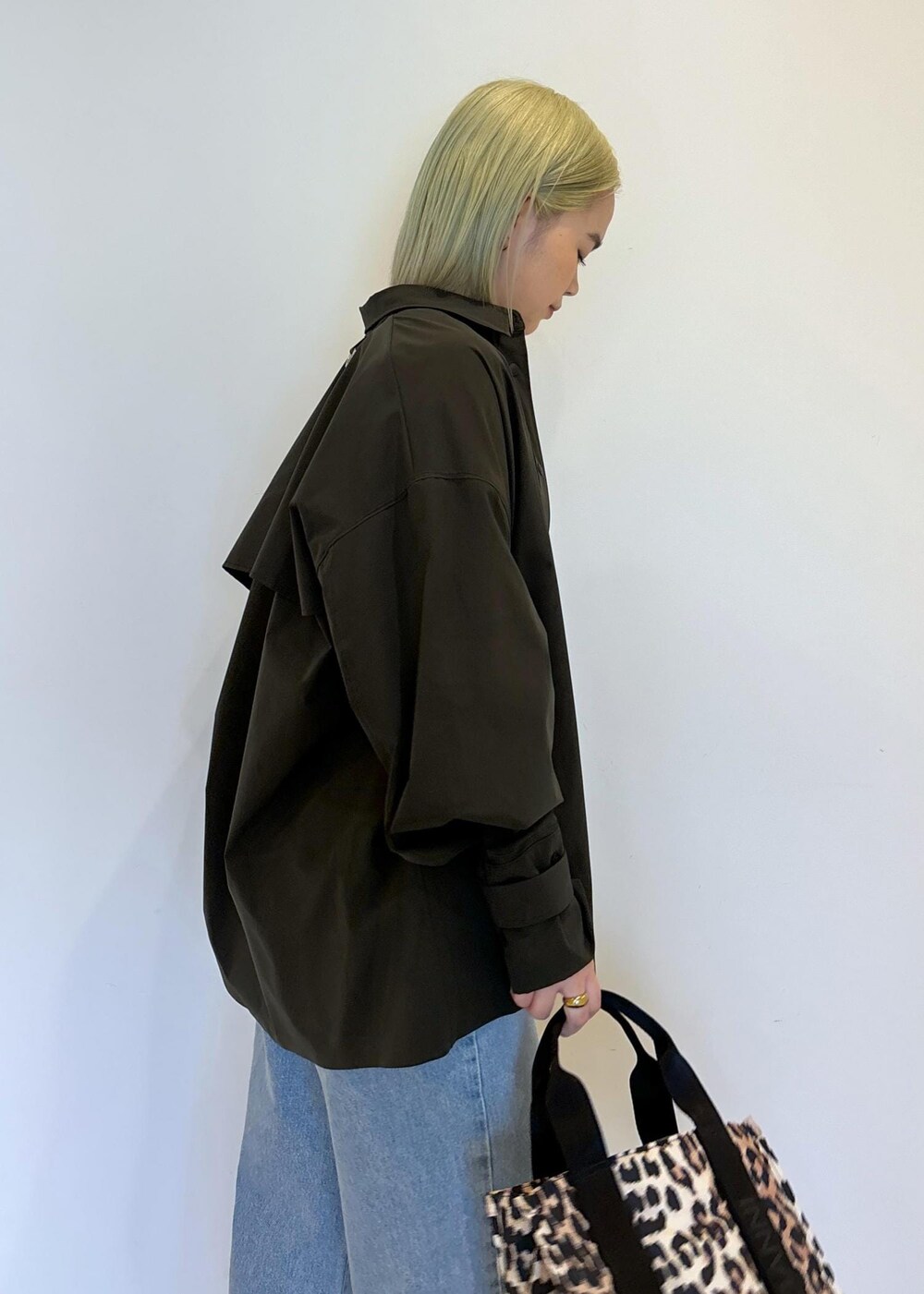 ホワイト系のタンクトップ、ブラウン系のショルダーバッグ、ブルー系のデニムパンツを着用したレディースの春コーディネートの8枚目の写真