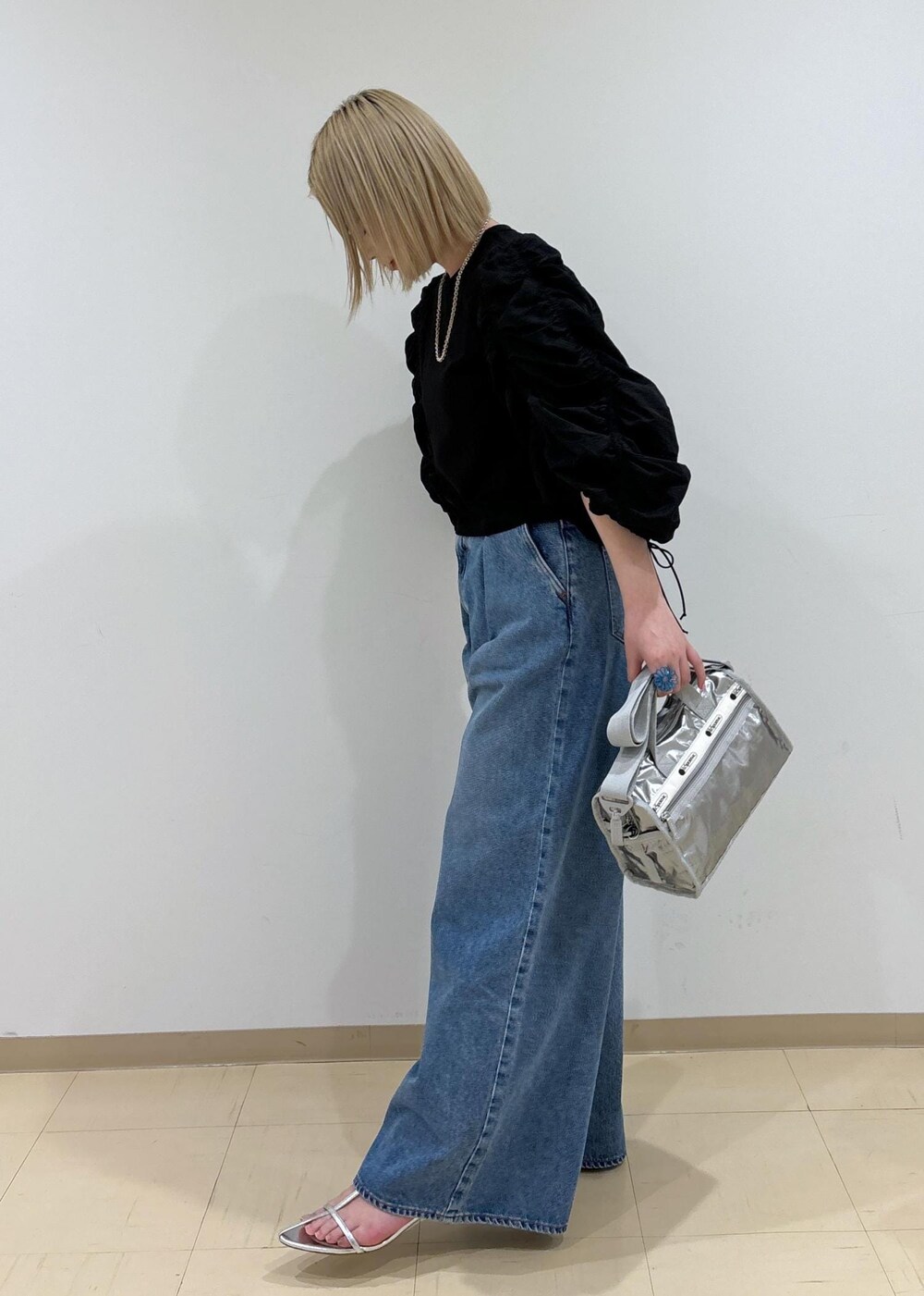 ブルー系のデニムパンツ、シルバー系のショルダーバッグ、シルバー系のサンダルを着用したレディースの春コーディネートの2枚目の写真