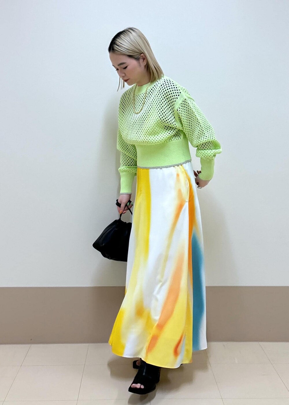 イエロー系のワンピース、ブラック系のショルダーバッグ、ブラック系のブーツを着用したレディースの春コーディネートの2枚目の写真