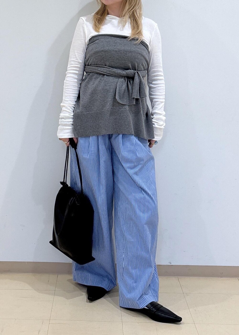 グレー系のニット/セーター、ブラック系のサンダル、ブラック系のショルダーバッグを着用したレディースの秋コーディネートの5枚目の写真