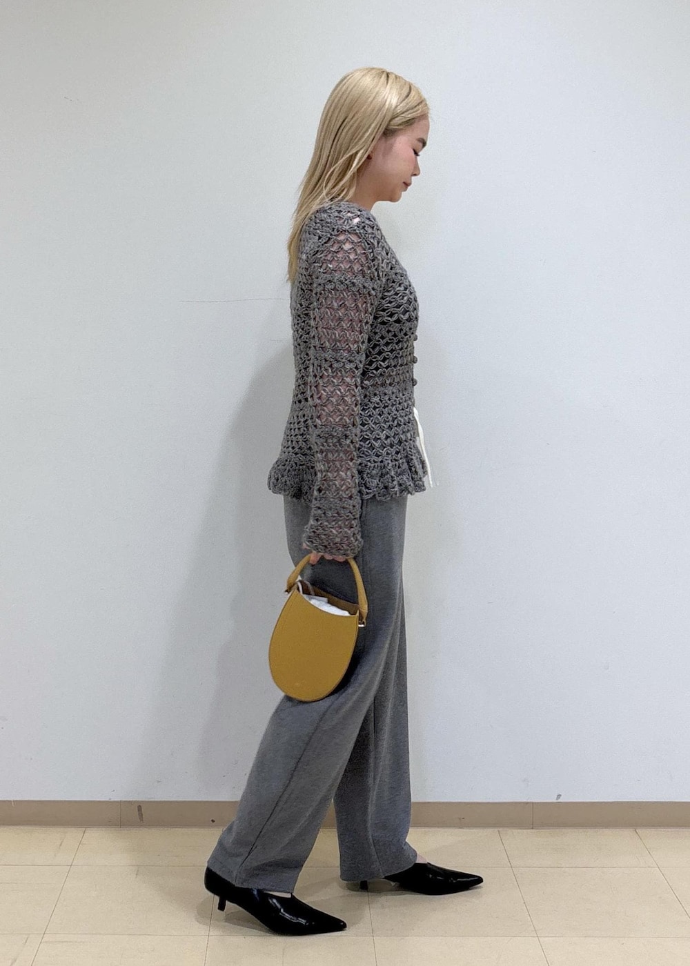ブラック系のパンプス、イエロー系のハンドバッグ、グレー系のカーディガン/ボレロを着用したレディースの秋コーディネートの4枚目の写真