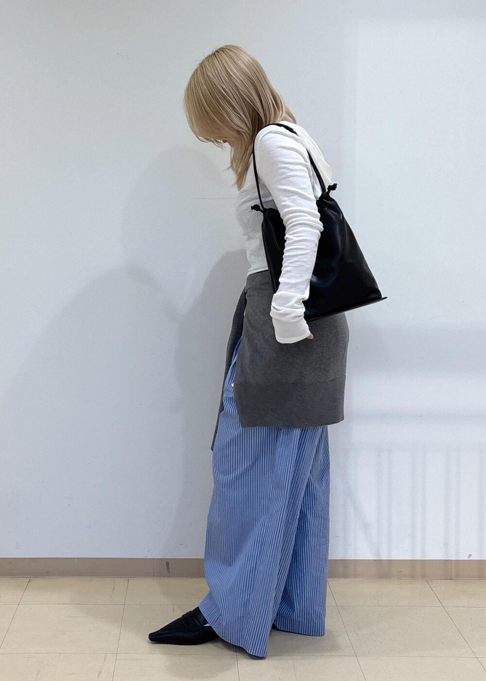 グレー系のニット/セーター、ブラック系のサンダル、ブラック系のショルダーバッグを着用したレディースの秋コーディネートの2枚目の写真