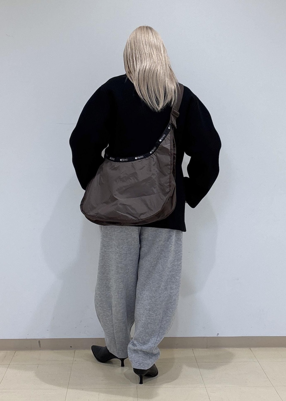 ブラック系のブーツ、グレー系のその他パンツ、ブラウン系のショルダーバッグを着用したレディースの冬コーディネートの3枚目の写真
