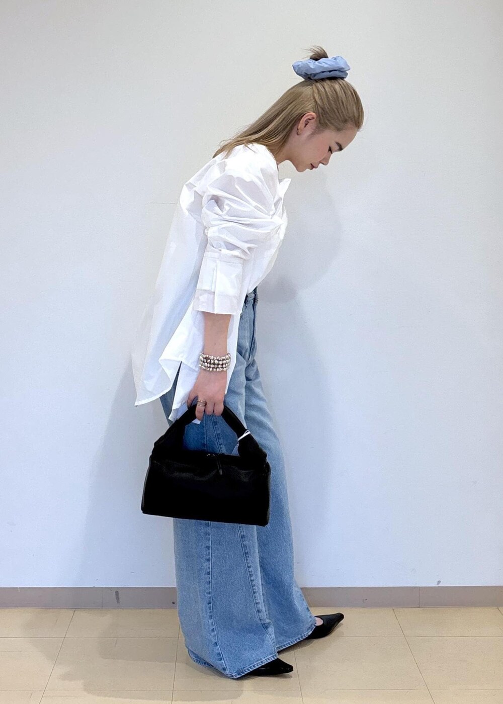 ブルー系のデニムパンツ、ブラック系のサンダル、ブラック系のハンドバッグを着用したレディースの春コーディネートの4枚目の写真