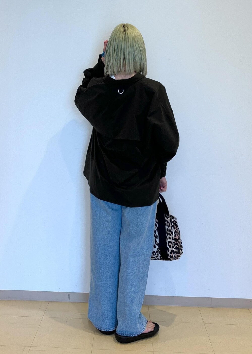 ホワイト系のタンクトップ、ブラウン系のショルダーバッグ、ブルー系のデニムパンツを着用したレディースの春コーディネートの3枚目の写真