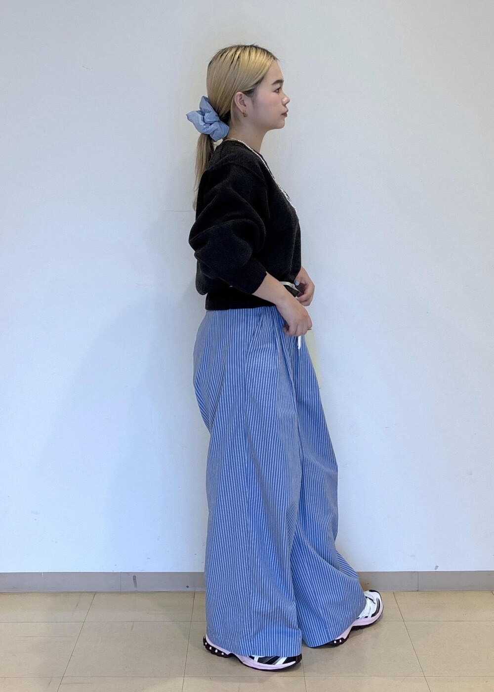 ブルー系のスラックス、グレー系のニット/セーターを着用したレディースの秋コーディネートの4枚目の写真