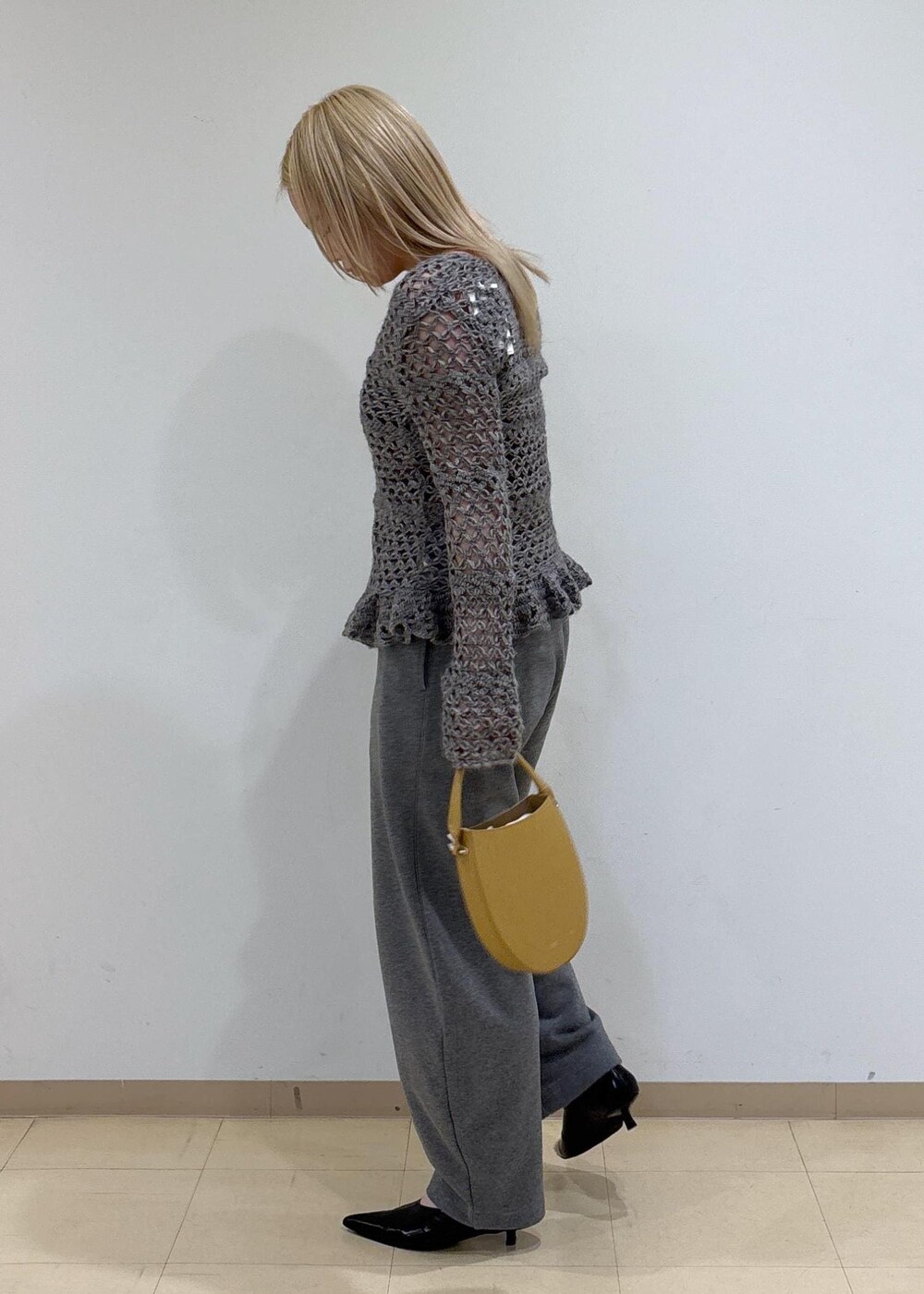 ブラック系のパンプス、イエロー系のハンドバッグ、グレー系のカーディガン/ボレロを着用したレディースの秋コーディネートの2枚目の写真