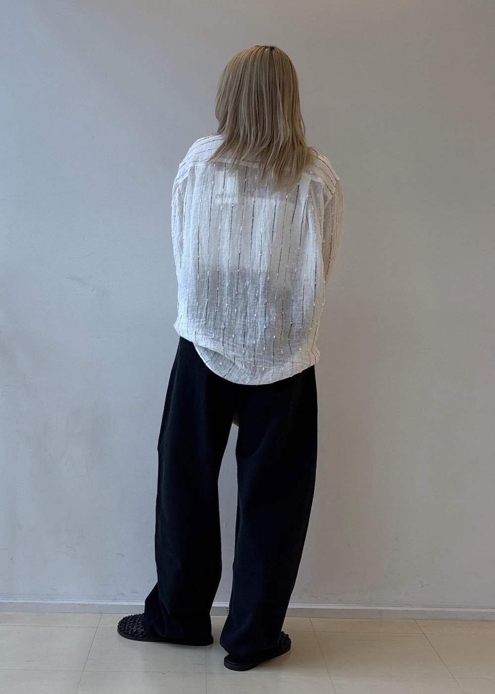 ブラック系のデニムパンツ、ブラック系のサンダル、ホワイト系のシャツ/ブラウスを着用したレディースの夏コーディネートの3枚目の写真
