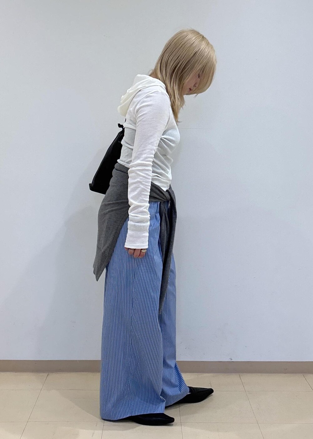 グレー系のニット/セーター、ブラック系のサンダル、ブラック系のショルダーバッグを着用したレディースの秋コーディネートの4枚目の写真