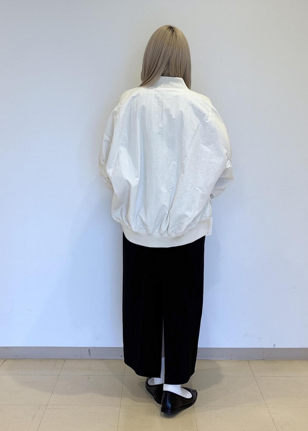 ブラック系のハンドバッグ、ホワイト系のTシャツ/カットソー、ブラック系のバレエシューズを着用したレディースの冬コーディネートの3枚目の写真