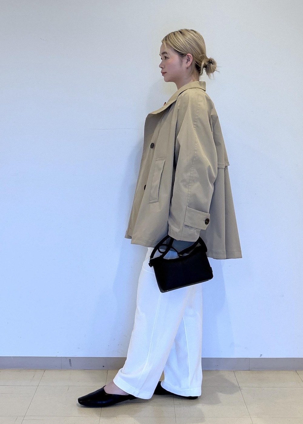 ベージュ系のトレンチコート、レッド系のTシャツ/カットソー、ブラック系のサンダルを着用したレディースの春コーディネートの2枚目の写真