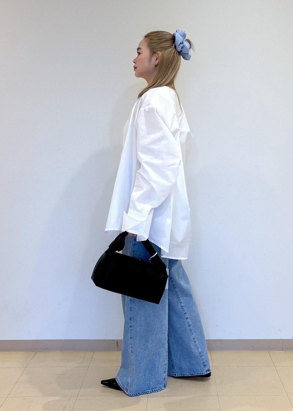 ブルー系のデニムパンツ、ブラック系のサンダル、ブラック系のハンドバッグを着用したレディースの春コーディネートの2枚目の写真