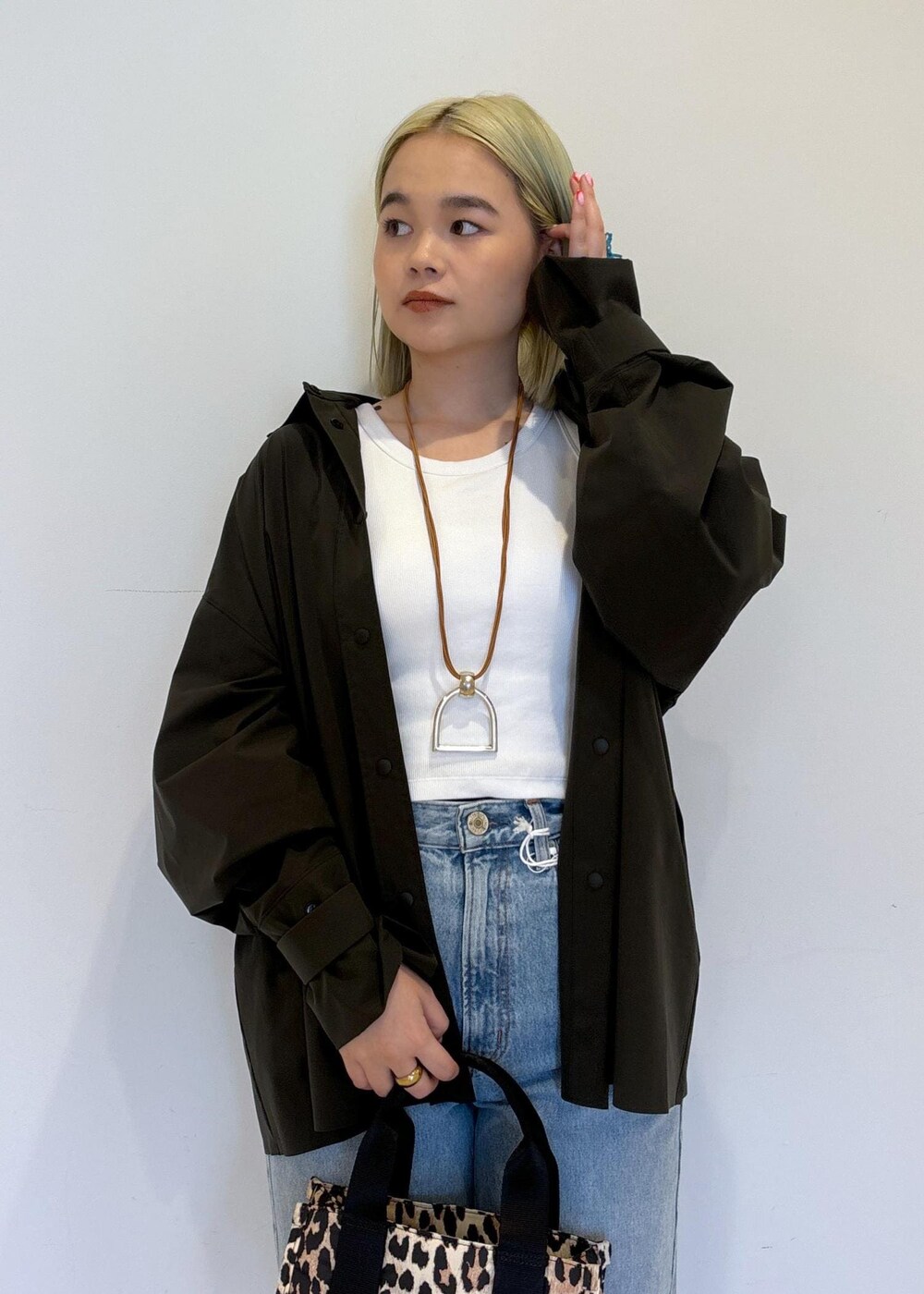 ホワイト系のタンクトップ、ブラウン系のショルダーバッグ、ブルー系のデニムパンツを着用したレディースの春コーディネートの5枚目の写真