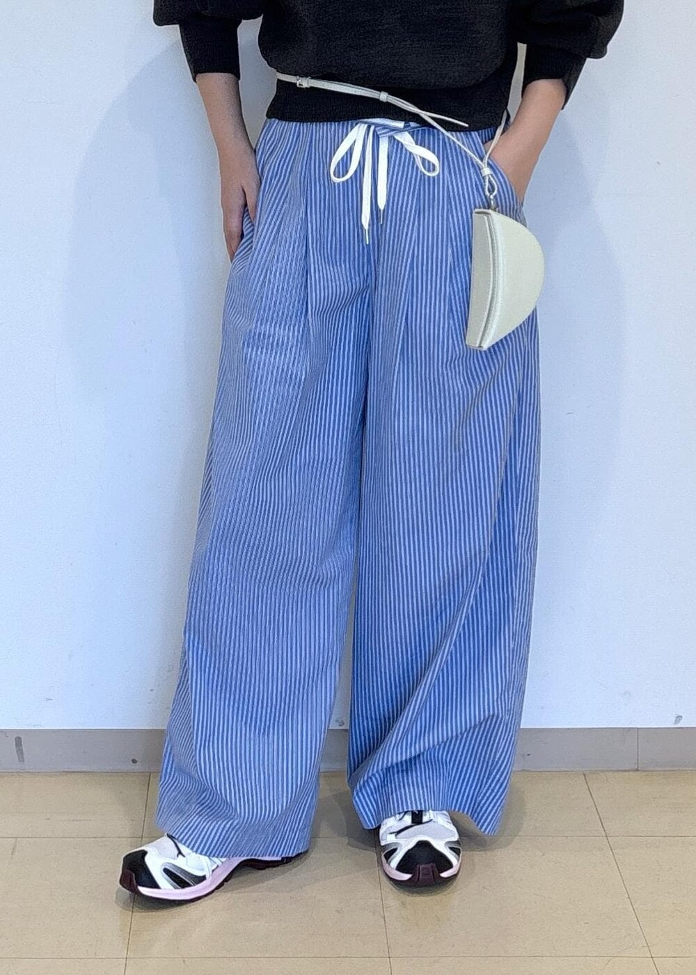 ブルー系のスラックス、グレー系のニット/セーターを着用したレディースの秋コーディネートの6枚目の写真