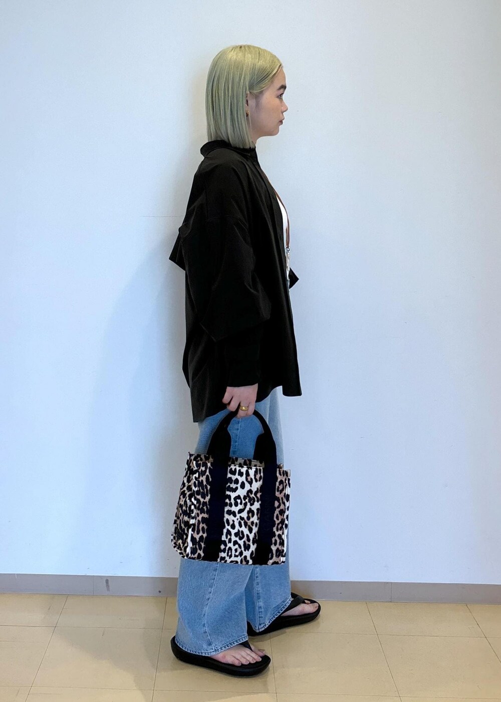 ホワイト系のタンクトップ、ブラウン系のショルダーバッグ、ブルー系のデニムパンツを着用したレディースの春コーディネートの4枚目の写真