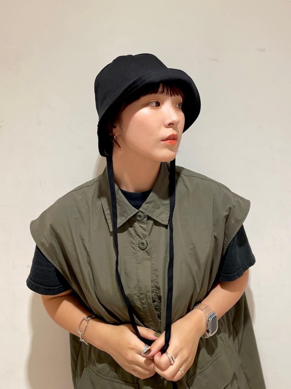 グリーン系のベスト、ブラック系のTシャツ/カットソー、グレー系のスカートを着用したレディースの夏コーディネートの2枚目の写真