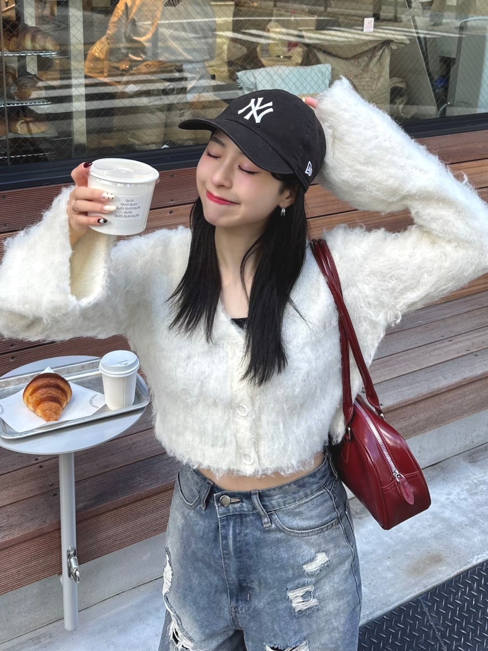 ホワイト系のカーディガン/ボレロ、レッド系のショルダーバッグ、ブルー系のデニムパンツを着用したレディースの秋コーディネートの2枚目の写真