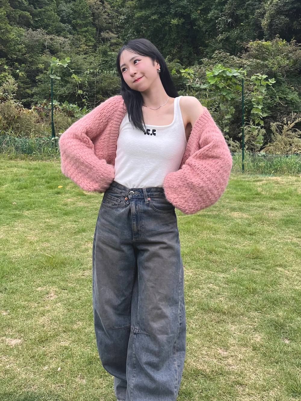 ホワイト系のタンクトップ、ピンク系のカーディガン/ボレロ、ブルー系のデニムパンツを着用したレディースの秋コーディネートの2枚目の写真