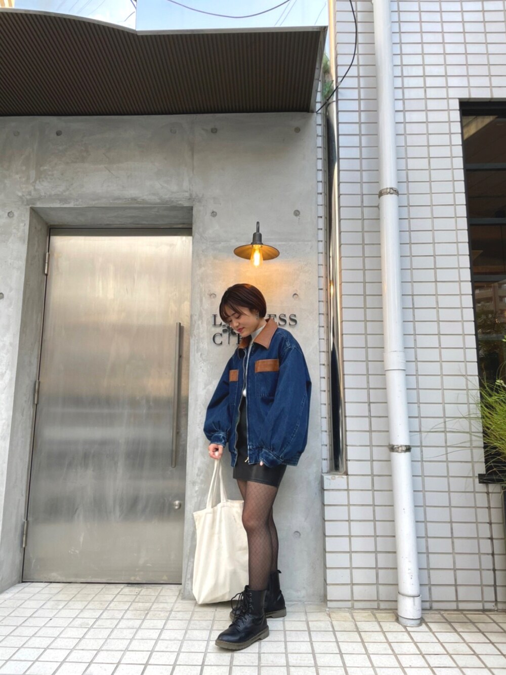 ブラック系のブーツ、ブラック系のスカート、ブルー系のデニムジャケットを着用したレディースの秋コーディネートの2枚目の写真