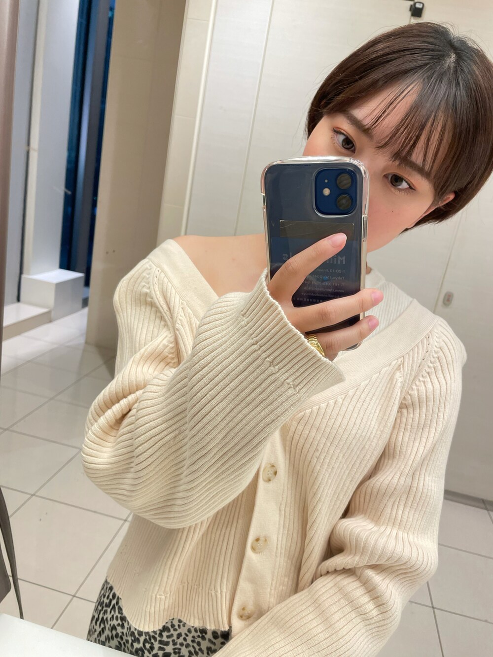 ベージュ系のカーディガン/ボレロ、ホワイト系のスカート、ブラック系のスリッポンを着用したレディースの秋コーディネートの3枚目の写真