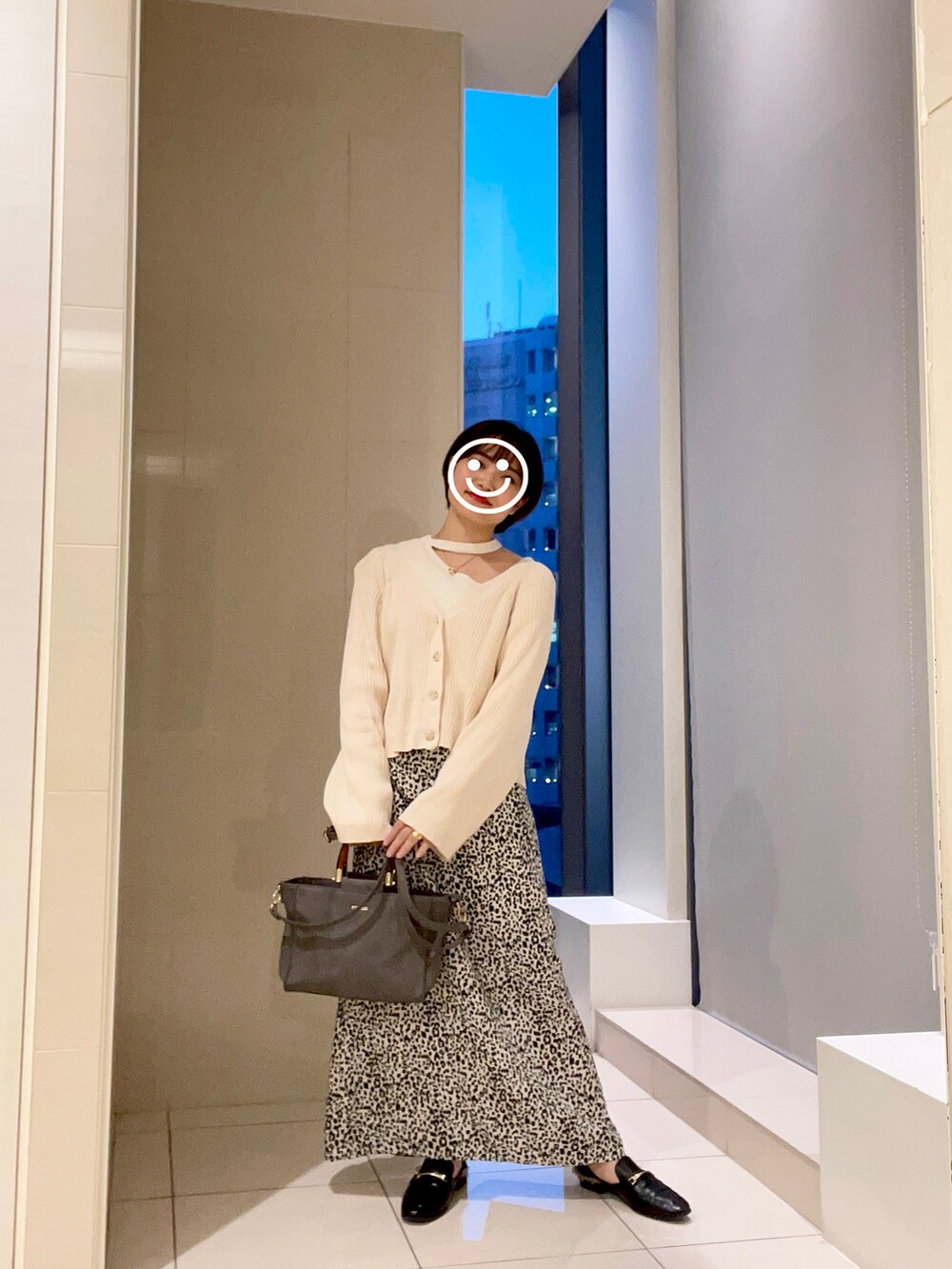 ベージュ系のカーディガン/ボレロ、ホワイト系のスカート、ブラック系のスリッポンを着用したレディースの秋コーディネートの2枚目の写真