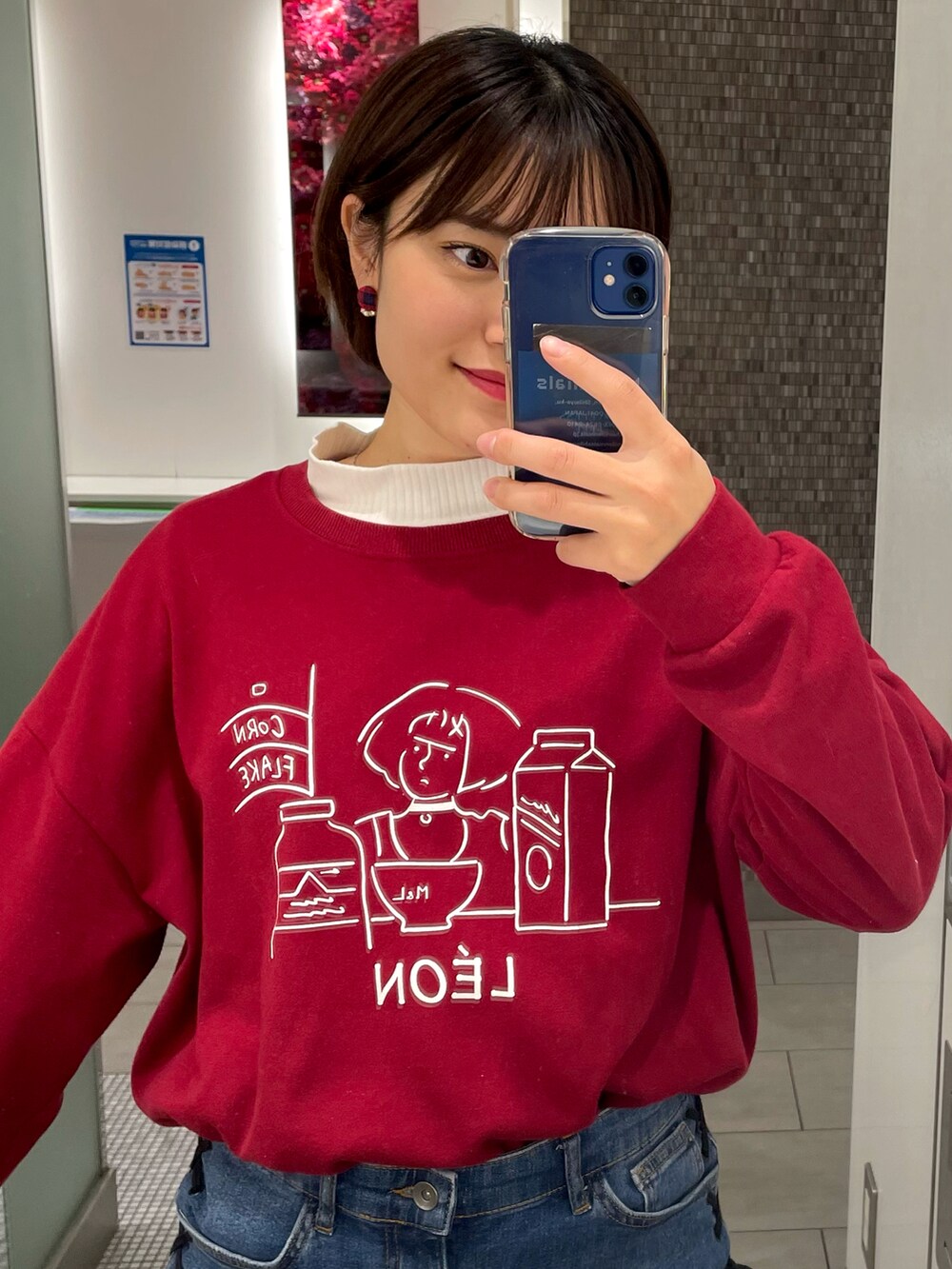 レッド系のスウェット、ブルー系のデニムパンツ、ブラック系のブーツを着用したレディースの秋コーディネートの4枚目の写真