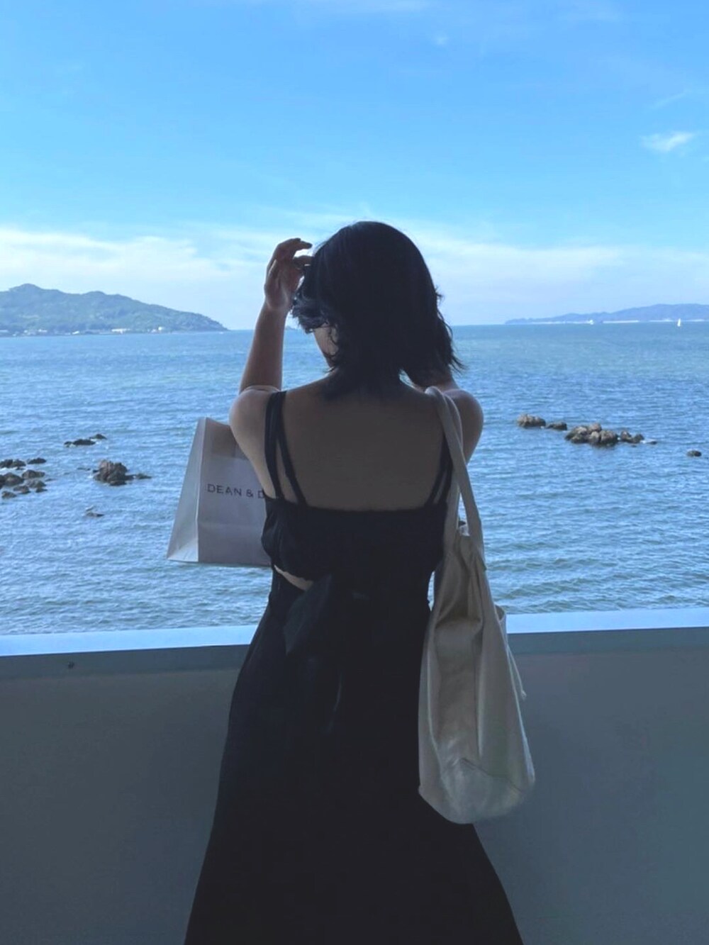 ブルー系のサンダル、ベージュ系のトートバッグ、ブラック系のワンピースを着用したレディースの秋コーディネートの2枚目の写真